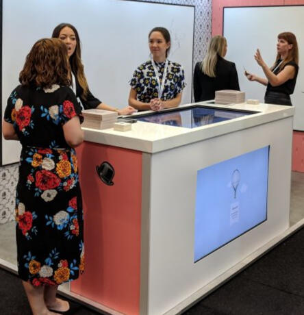 Image of a man in a suit standing while shaking the hand of a woman seated.